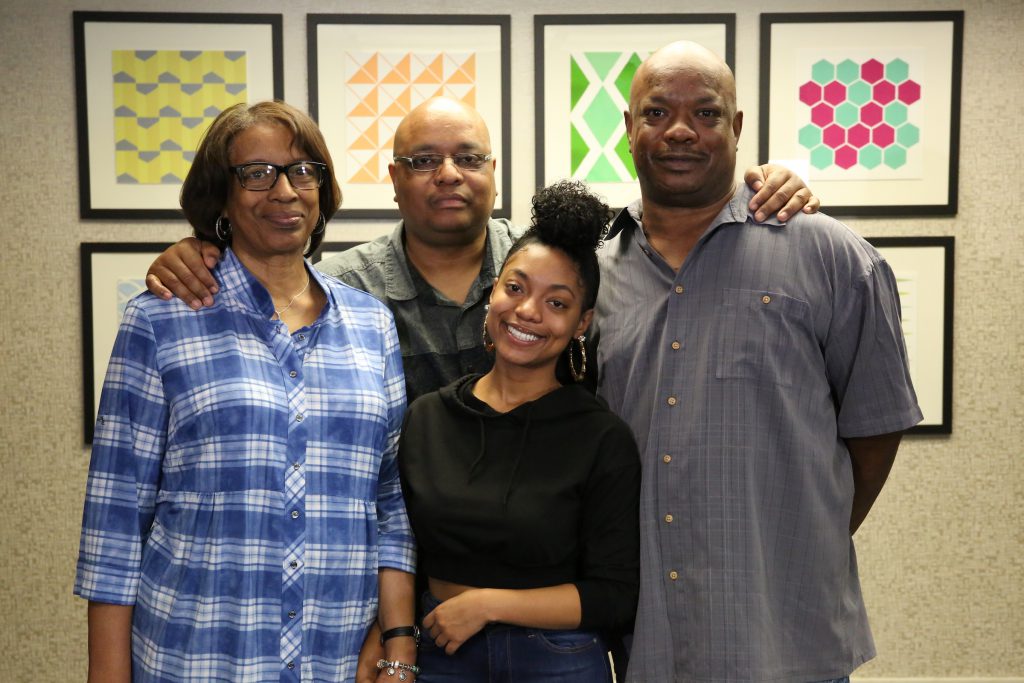 A family poses for the camera in front of framed abstract art pieces.