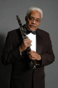 A Black man holding a clarinet